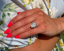 Load image into Gallery viewer, Photo of platinum three-stone engagement ring featuring a 7.63CT pear-shaped diamond centered between two smaller pear-shaped diamonds on a hand.