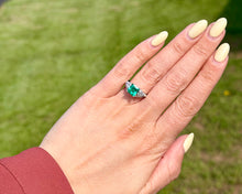 Load image into Gallery viewer, Hand wearing an emerald and diamond ring.