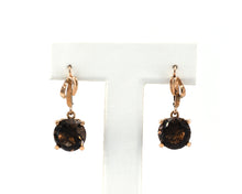 Load image into Gallery viewer, Vintage 14K yellow gold drop earrings featuring large round smokey quartz gemstones in a free form four-prong setting with lever-back clasps, displayed on a white stand.