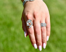 Load image into Gallery viewer, Vintage Diamond Flower Ring and Band on a Hand with a Blurred Green Background.