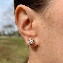 Load image into Gallery viewer, Close-up of an ear wearing a vintage enameled diamond stud earring with a blurred outdoor background