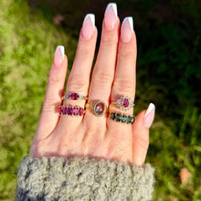 Load image into Gallery viewer, Hand wearing yellow gold pink, green, and watermelon tourmaline rings against a blurred green background.