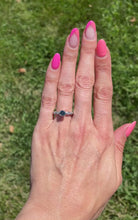 Load and play video in Gallery viewer, Vintage platinum ring set in the center with a color enhanced fancy blue round diamond, with white diamond side stones video sparkling in the sun.