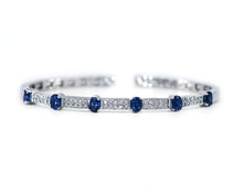 Load image into Gallery viewer, Product photo of 18K white gold flexible cuff bracelet set with alternating oval blue sapphires and pavé diamond links. 
