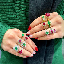Load image into Gallery viewer, Hands wearing multiple emerald, ruby, and diamond rings with gemstones against a green sweater background.
