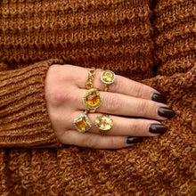 Load image into Gallery viewer, Hand wearing multiple gold rings with citrine gemstones against a brown sweater background
