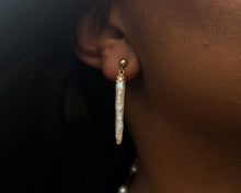 Load image into Gallery viewer, Close-up profile on a person wearing a long vintage dangle earring featuring a 14K yellow gold ball stud and decorative cup holding a slender, elongated natural-shaped white pearl.
