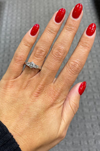 14k white gold three stone round brilliant cut diamond engagement ring on hand.