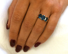 Load image into Gallery viewer, 14k yellow gold and London blue topaz three stone ring on hand.
